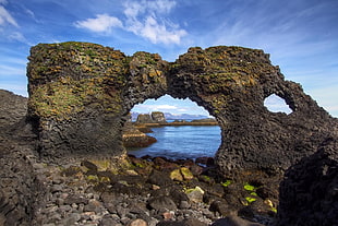 gray rock formation beside body of water photo during daytime